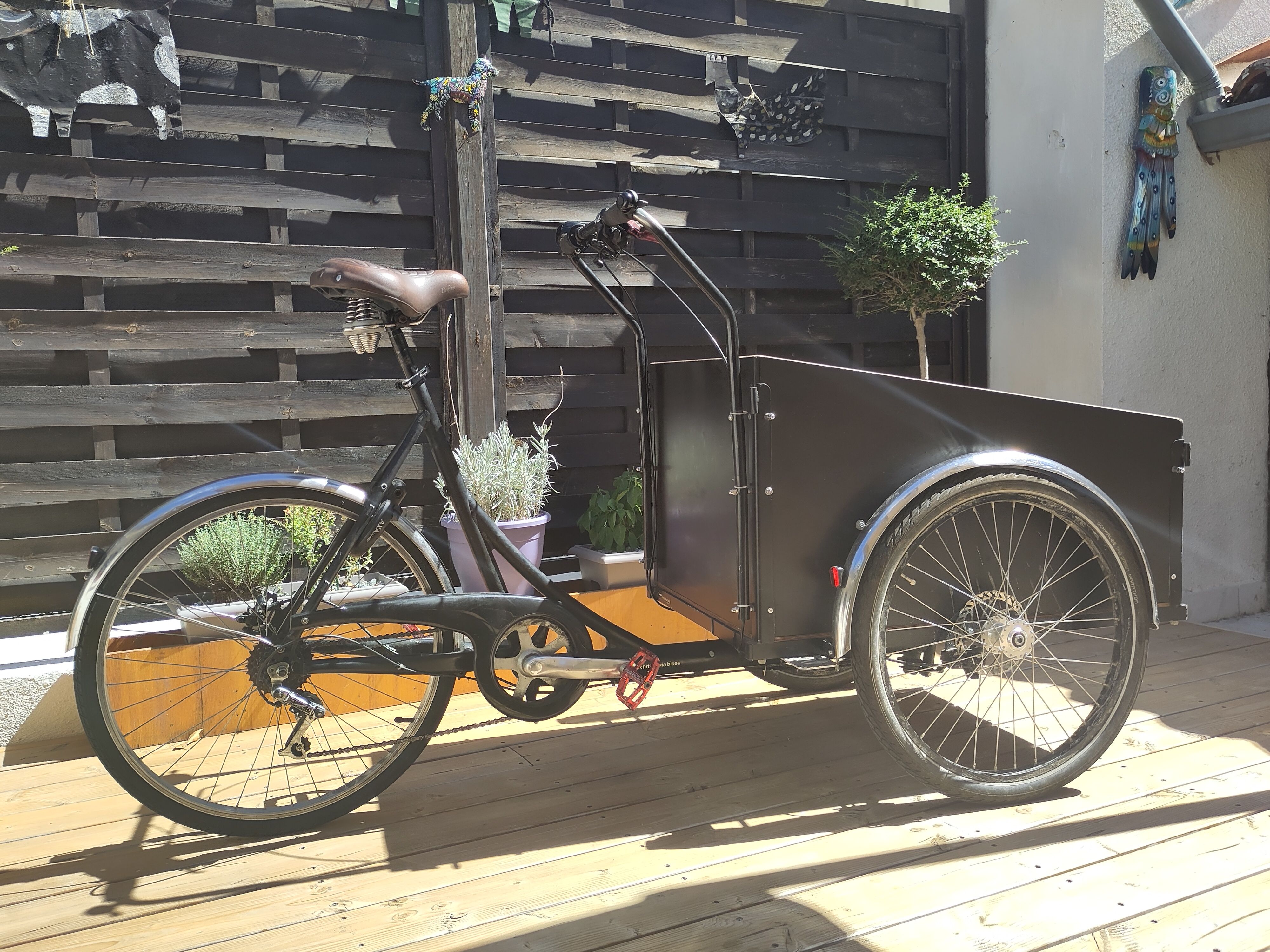 Cargo bike on deck with wood fence in background.