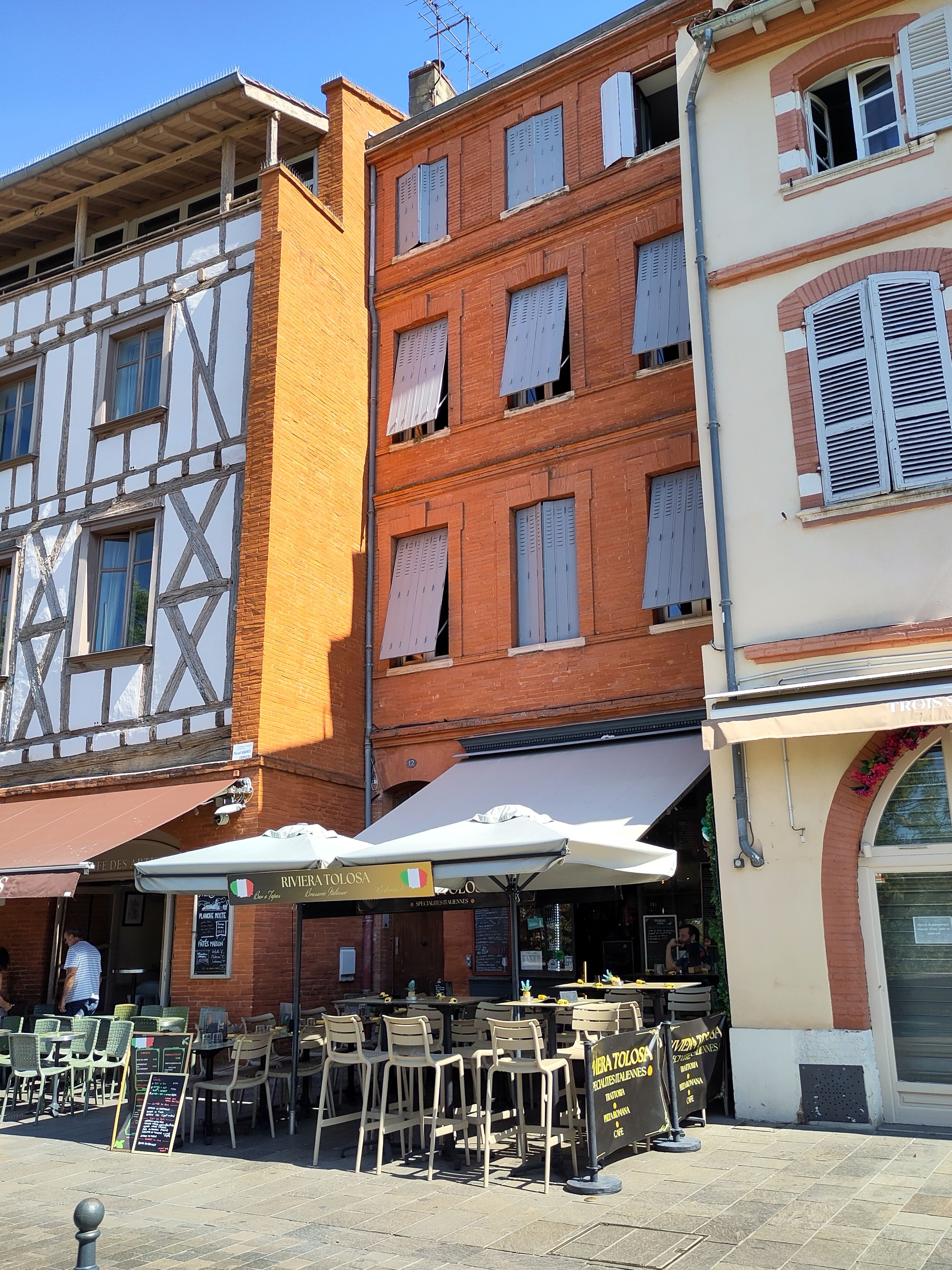 Three story brick building with cafe seating.