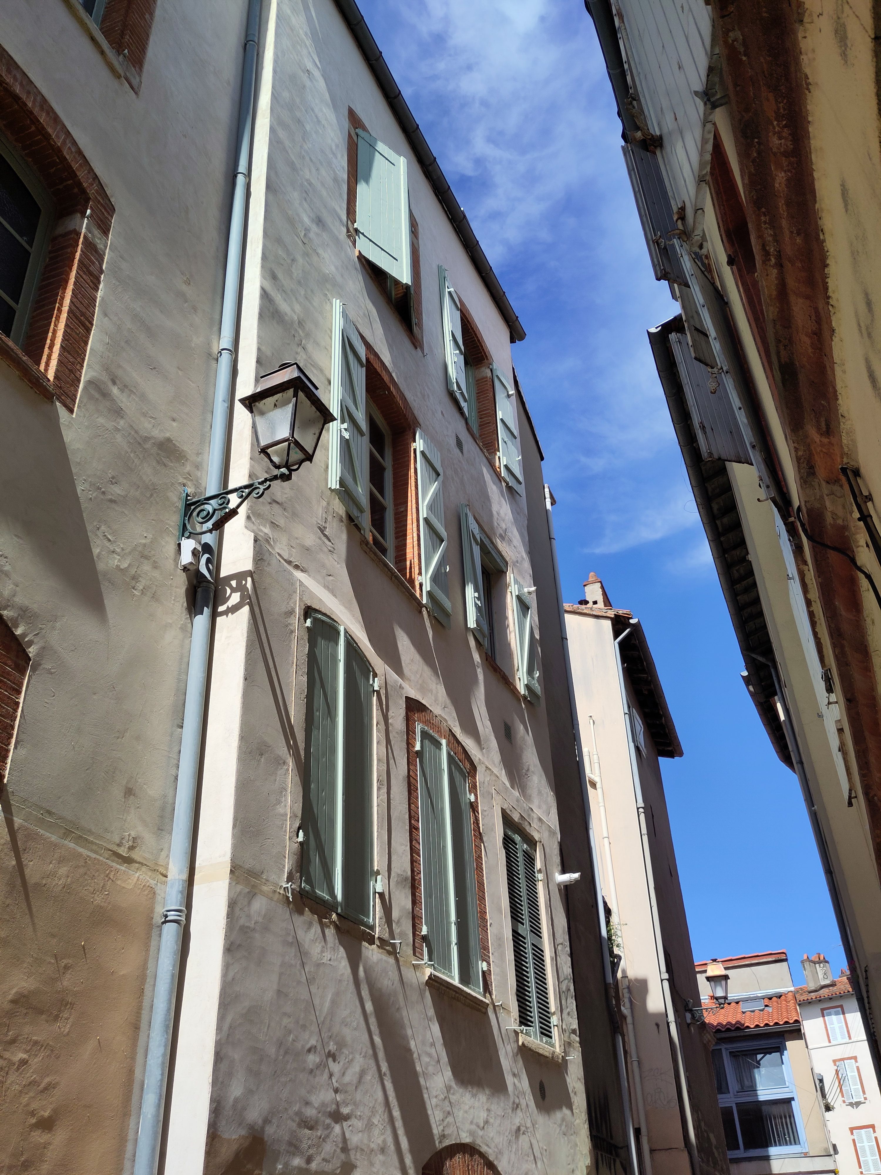 Traditional 4 story building in Toulouse with vertical windows and wood frames.