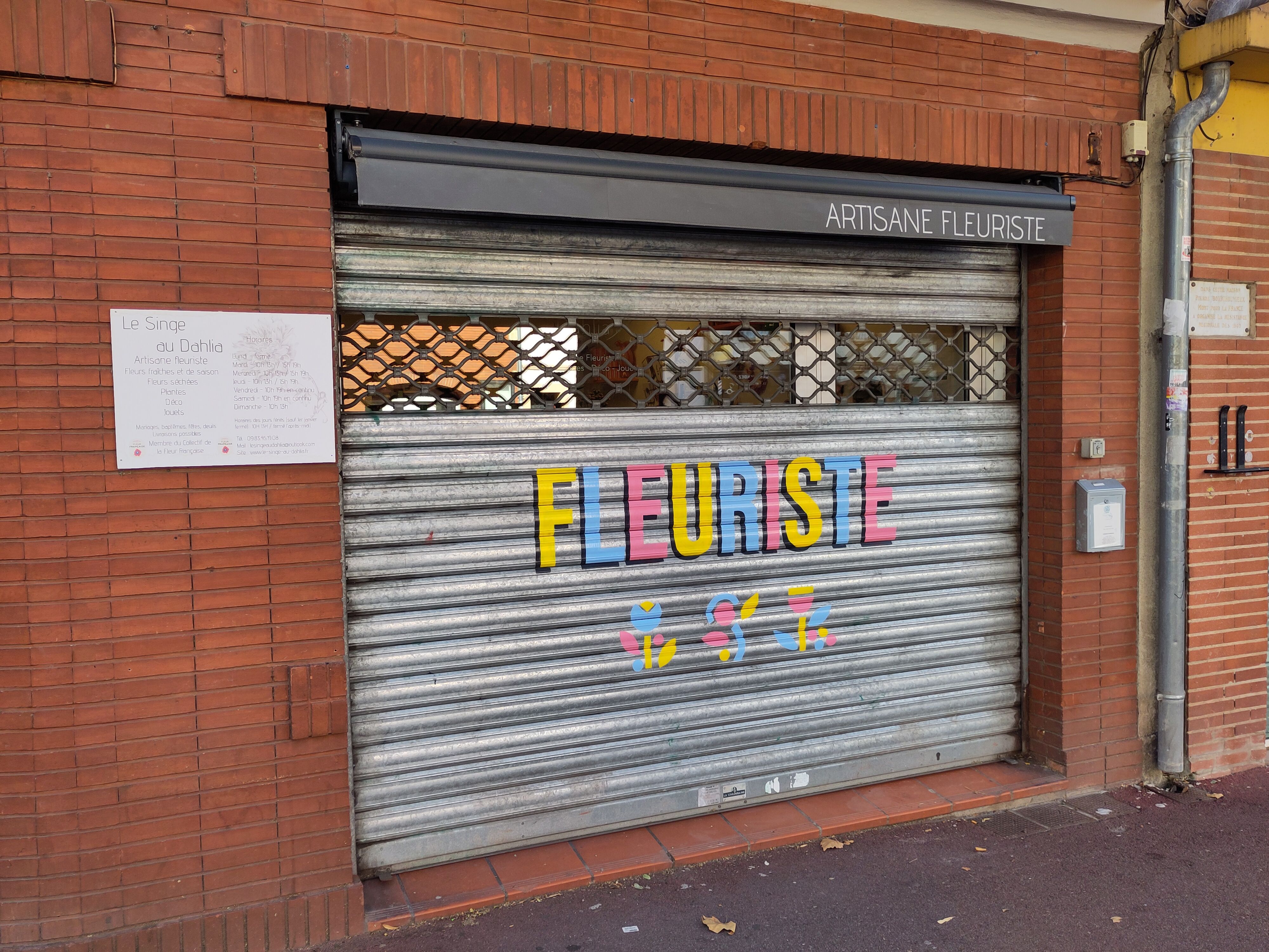 Florist shop with closed shutter in red brick building.